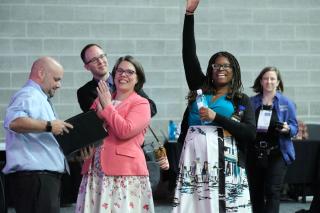 UUA Co-Moderator Elandria Williams (with arm raised) cheers beside President Susan Frederick-Gray and Co-Moderator Mr. Barb Greve from the sidelines of the Opening Ceremony of the 2019 UUA General Assembly in Spokane, Washington