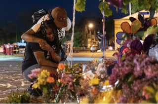 Pleazant Davis, 22, is comforted by Tasha Dixon, 35, at a memorial across the street from the store in Buffalo where Saturday's shooting occurred