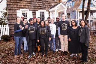 A multiracial group of people standing in the front yard of a house.