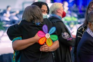 Rev. Gianni Fogliano, the UUA’s manager and strategist for Equity, Belonging, and Change, holds an Article II Shared Values flower while embracing former UUA President Susan Frederick-Gray at General Assembly 2023.