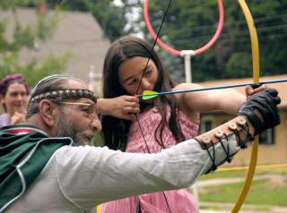 Helena Esparza gets an archery lesson from “Merlin” at KentHogwarts, a Harry Potter-themed summer camp run by the Unitarian Universalist Church of Kent, Ohio.