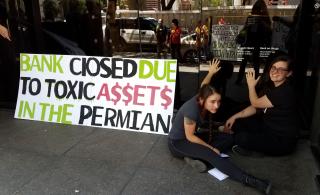 Meagan Bluestein and Aly Tharp, program director of UU Ministry for Earth, glue themselves to the door of a Chase Bank in Austin, Texas, during an Extinction Rebellion action protesting Chase’s support of fossil fuel extraction.