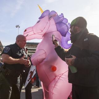 Police officers tell the Rev. Forrest Gilmore, who is dressed as a pink and purple unicorn, to leave before arresting him at a farmers' market in Bloomington, Indiana, where he and others have been protesting a vendor with ties to white supremacy groups.