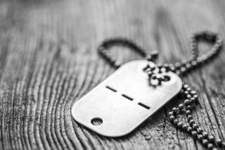 Old blank dog tag with chain on wooden background.