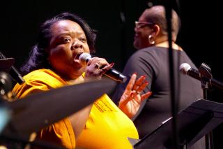 Cecilia Hayes sings during the Service of the Living Tradition at the 2018 General Assembly; Amanda M. Thomas conducts the choir in the background