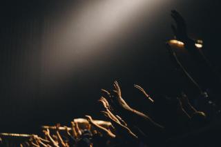 Photo of raised hands at a concert. black background