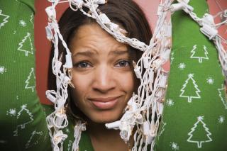Stock image of woman holding up a tangle of holiday lights.