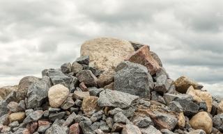 Pile of huge rocks and boulders under dark grey sky - Stock image