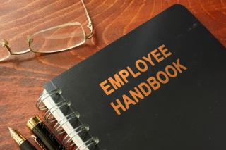 Employee handbook on a wooden table and glasses. - Stock image