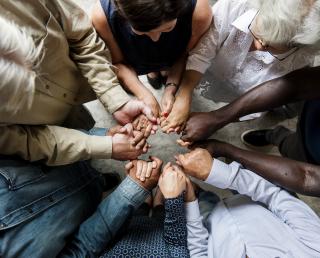 Group of diverse hands holding each other support together teamwork aerial view - Stock image