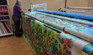Pat Sturtzel works the long arm quilting machine for a collaborative quilt.