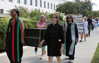 Interfaith clergy (including Unitarian Universalist the Rev. Robin Tanner, center) carry a cardboard coffin while leading a procession to protest attempts to repeal the ACA, Washington, D.C., on July 25, 2017.