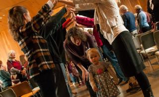 Congregants at the UU Fellowship of Central Oregon forming a bridge with their hands for others to walk through. 