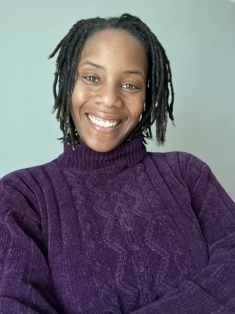 Headshot of Jasmine Vaughn-Hall smiling and wearing a purple sweater