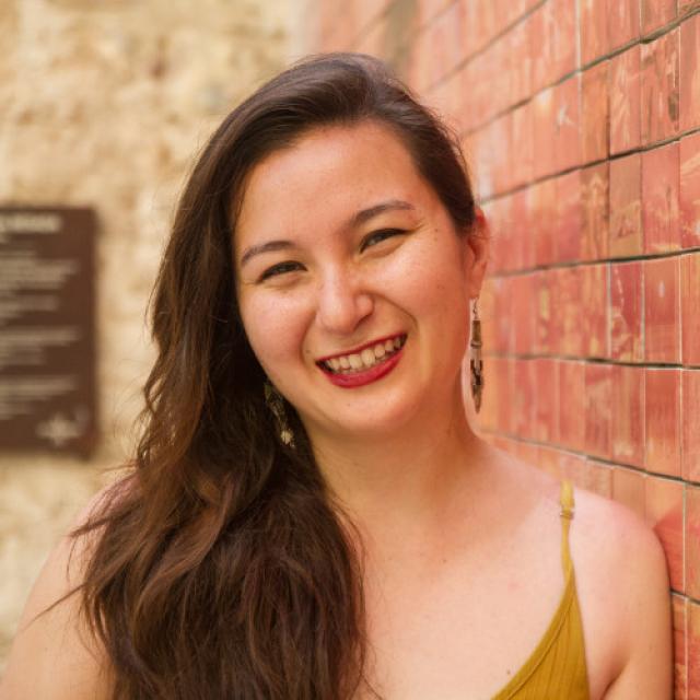 A woman smiling in front of a brick wall