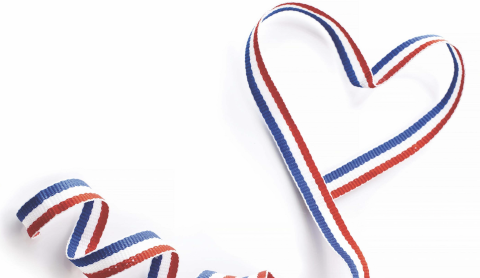 Red, white and blue heart shaped ribbon against white background