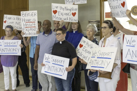 A group of people holding protest signs in favor of expanding Medicaid in North Carolina.